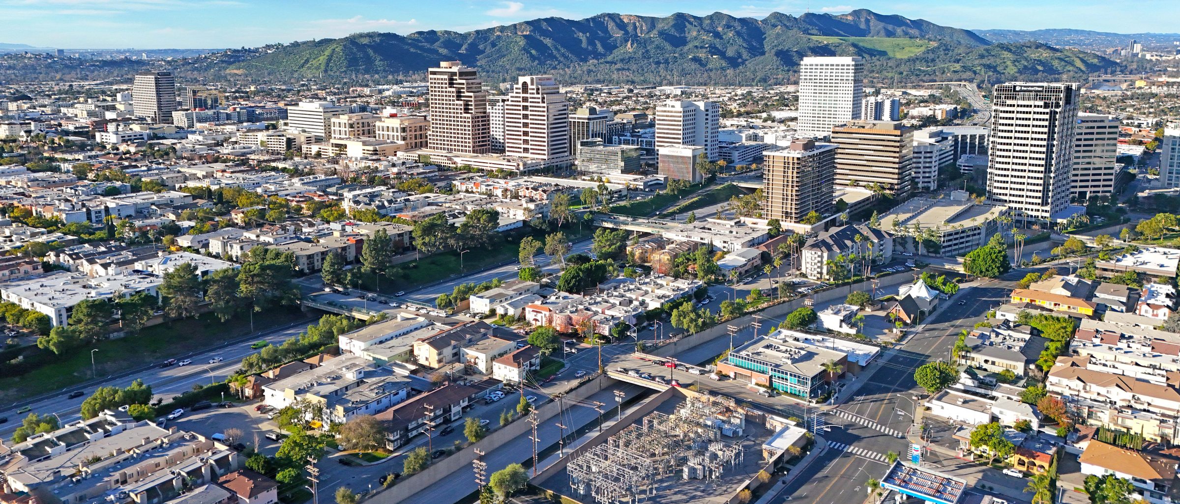 Aerial view of Glendale skyline with San Gabriel Mountains in the background, showing residential apartment buildings and street grid.
